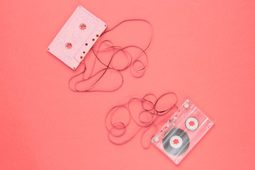 Music lover minimalism concept. Retro style 80s. Two audio cassettes with film on pink paper background.