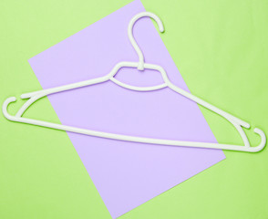 White plastic hanger on colored background. Top view