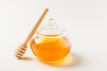 Glass jar of honey with honey dipper isolated on a white background with space for text 