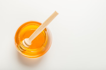 Glass jar of honey with honey dipper isolated on a white background with space for text 