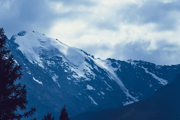 Naklejka na ściany i meble Mountain range under cloudy sky. Snowy peaks of mountains rocks
