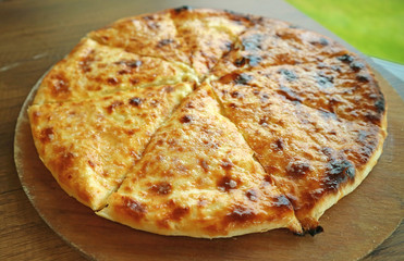 Fresh Baked Cheese-filled Georgian Flatbread Khachapuri Imeruli (Imeretian) on a Wooden Plate