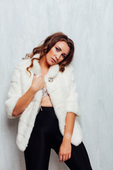 portrait of a beautiful fashionable woman with hair curls in a white fur coat