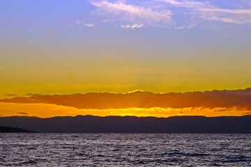 Gorgeous view of sunset on Lake Geneva with golden sun rays spreading from behind the clouds, Vevey, Switzerland.