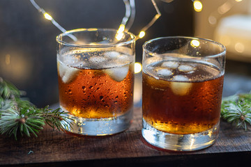 Whiskey in glasses with ice and perspiration on a dark background.