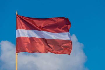 Fototapeta na wymiar The flag of Latvia flying in breeze wind on sky background