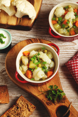Cauliflower vegetables soup in bowl, bread, cream and raw cauliflower
