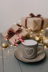 cup of coffee with  candy cane on a background of gifts