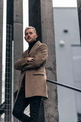 Selective focus of handsome businessman standing in beige coat.