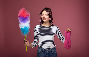A girl in curlers and gloves for cleaning holds pipidaster in her hands.