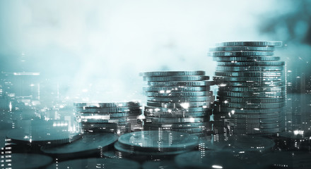 Double exposure of city and stack of coins for finance and banking concept