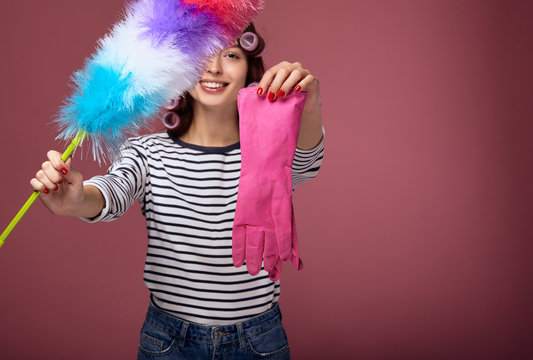 The girl is holding a pipidaster and a pink rubber glove.