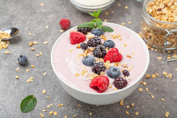 Berry smoothie bowl topped with blueberries, raspberry, blackberry, coconut flakes, yoghurt, muesli and mint for healthy breakfast, selective focus. Vegan food