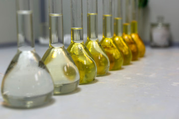 Closeup  a long row of glass flasks with a yellow solution on a laboratory bench. Increase the...