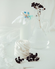 Handmade air russian fruitwhite marshmallow on a white background with beautiful bottles and dry berries. Homemade Sweets.