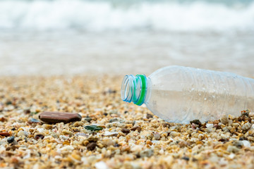 Close up plastic bottle on sand beach. Plastic pollution of nature. Ecology and environment concept. Waste emission to ocean.