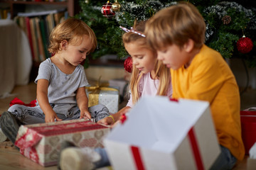 Happy children opening Christmas gift at home.