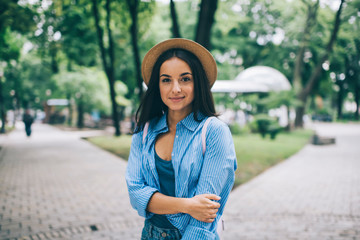 Half length portrait of attractive trendy dressed woman posing outdoors and looking at camera...