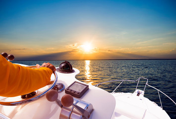 Hand of captain on steering wheel of motor boat in the blue ocean during the fishery day. Success...