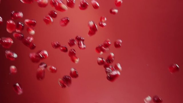 Juicy grains of ripe pomegranate are falling on the red background