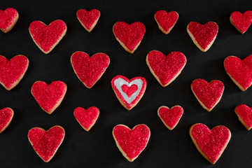 Red and white heart shaped cookies on black background, distinction concept, love symbol, valentine's day pattern