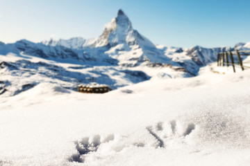 Hands shapes on fresh snow, with the background of the mountains and the Matterhorn.