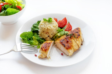 roasted chicken breast fillet with cauliflower risotto, lettuce and tomato on a white table, copy space, selected focus, narrow depth of field