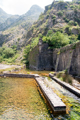 Fototapeta premium Kotor. Montenegro A river, shallowed by drought, near the old city against the backdrop of the mountains.