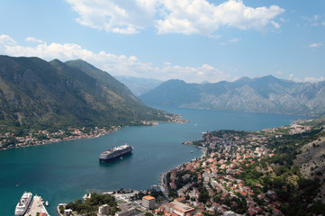 Fototapeta na wymiar Landscape from the mountains to the bay in the Adriatic Sea. Panorama of the old town on the shore with a cruise ship at sea.