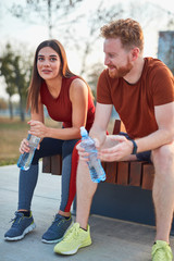 Modern couple making pause in an urban park during jogging / exercise.