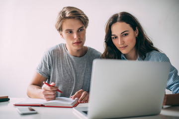 Skilled male and female students collaborating on college course work using university website with information for research, smart man and woman watching tutorial webinar during e learning indoors