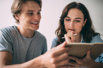 Positive male and female bloggers planning social publications for sharing to website, successful students reading information from textbook for education during studying cooperation process
