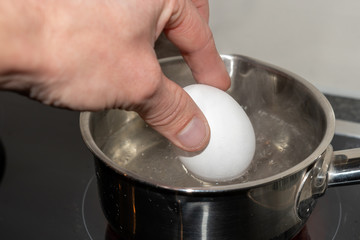 Ei in das kochende Wasser geben - Ei hartkochen