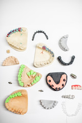 Various of artificial jaw models with dental implants and crowns on the white background, top view. Concept of aesthetic dentistry and implantation technology