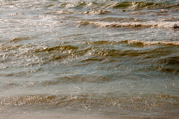 Black Sea. Water with waves. Mainly cloudy weather and sun rays. Blue and grey clouds. Before rain. Sand coast