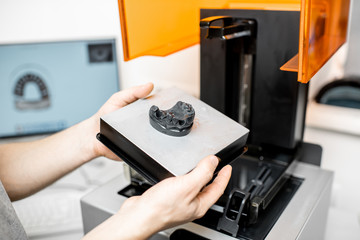 Dental technician removing jaw model from a 3d printer at the laboratory, modeling frame for...