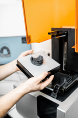Dental technician removing jaw model from a 3d printer at the laboratory, modeling frame for...