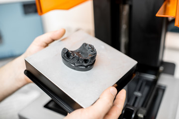 Dental technician removing jaw model from a 3d printer at the laboratory, modeling frame for implant production