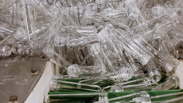 Plastic recycling industrial factory. Automatic conveyor lifting up plastic preforms for pet bottle manufacture. Production containers on plant from secondary raw materials. Chemical industry.