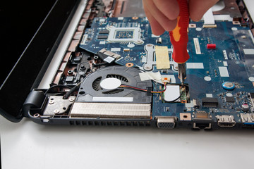 Electronics inside a laptop, laptop repair service. Screwdriver in the hand of a master.