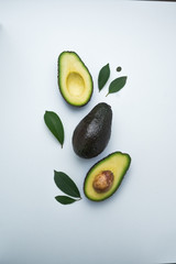 Avocados cut in halves forming a composition.on white background. Top view. White background. Healthy food.