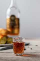 on a wooden table is a glass of cognac, a snack of a piece of dark chocolate and a bottle of alcohol