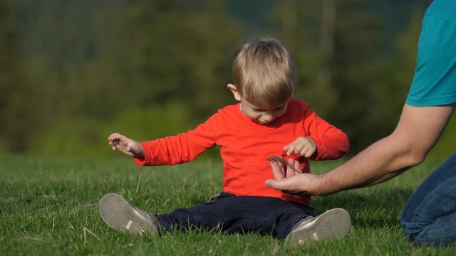 Father hand showing lizard to son in nature