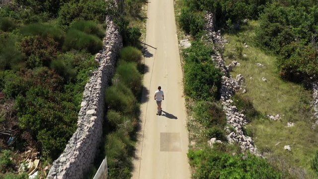 Following skateboarder on picturesque narrow paved road in Croatia