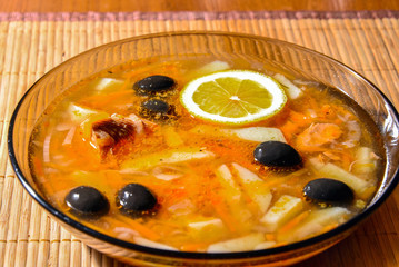 Fish soup Solyanka in a plate on a bamboo napkin. Russian cuisine. 
