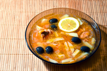 Fish soup Solyanka in a plate on a bamboo napkin. Russian cuisine. 