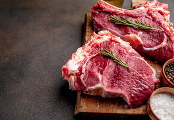 raw beef steaks with spices and rosemary on a stone background with copy space for your text