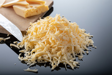 Grated cheese and a piece of cheese on a wooden board