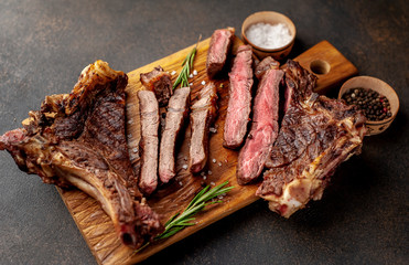 two grilled steaks with spices, with two types of frying on a stone background