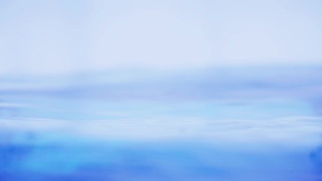 The clean water surface in slow motion fills the screen with water splashing shop the water drop and waving liquid surface with an air bubble. 1080p 29.97fps